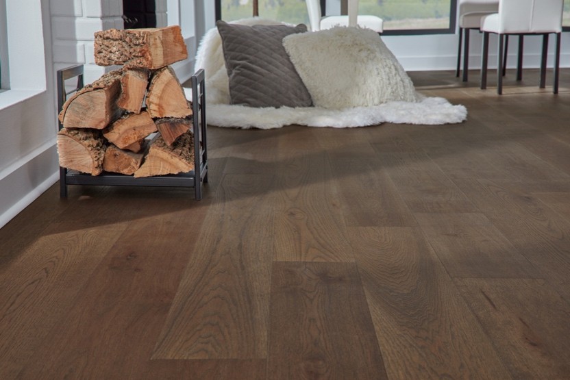 Wide-plank dark oak hardwood flooring installed in a modern living room next to a metal firewood rack